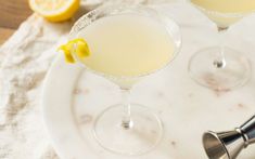 two martinis on a white plate with lemon wedges