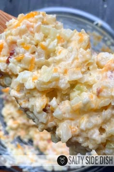 a wooden spoon full of potato salad on top of a glass bowl with the words salty side dish