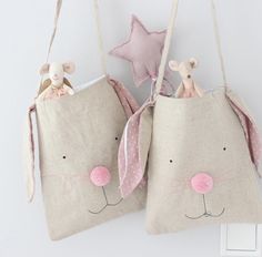 two small bags with stuffed animals in them hanging on a wall next to a light switch