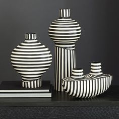 three black and white vases sitting on top of a table