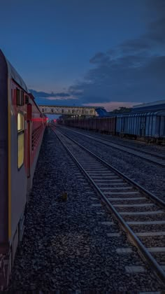 a train traveling down tracks next to a loading platform at night with the lights on