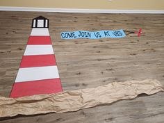 a paper plate lighthouse on the floor next to a sign that says come join us at yes