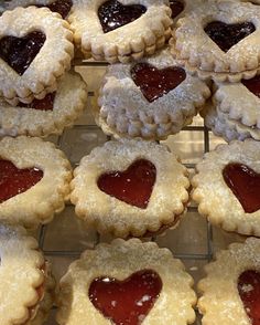 heart shaped cookies with jelly in the middle are cooling on a rack, ready to be eaten