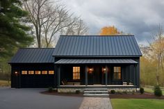 a black house with a metal roof and two garage doors on the front door is shown