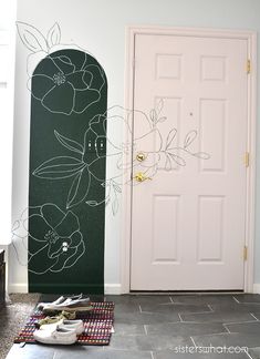 there is a door and some shoes on the floor in front of it with flowers painted on the wall