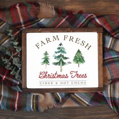 christmas trees cider and hot cocoa sign displayed on plaid blanket with fir tree logo