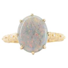 a ring with an oval opal surrounded by small yellow gold dots on the band