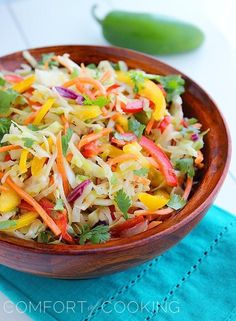 a wooden bowl filled with coleslaw and carrots on top of a blue towel