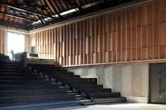 an empty auditorium with wooden walls and black seats on the second floor, looking towards the stage