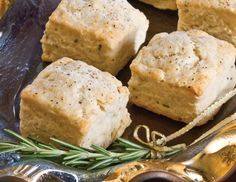 four biscuits on a plate with rosemary sprigs