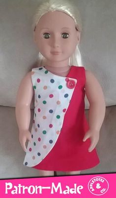 a doll with blonde hair wearing a red dress and polka dot bib, sitting on a couch