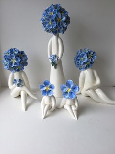 four white ceramic figurines with blue flowers in them