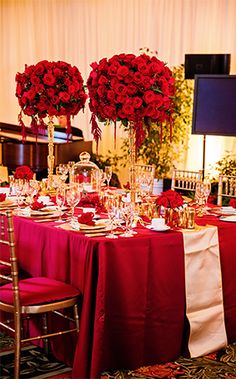 the table is set with red roses and place settings