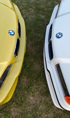 two cars parked next to each other in the grass with their hoods down and one is yellow