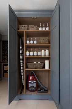 an open cabinet with many items in it and a vacuum cleaner on the floor next to it