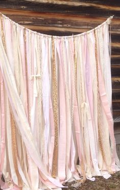 there is a pink and white curtain hanging from the side of a wooden wall with gold sequins on it