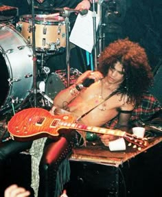 a shirtless man sitting in front of a guitar