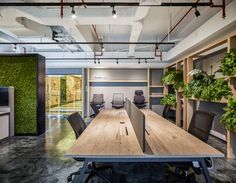 an empty conference room with wooden tables and chairs, plants on the wall behind them