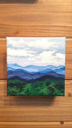 an acrylic painting of mountains and trees on a wood paneled wall, with the sky in the background