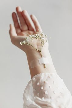 a woman's arm with a flower on it and a white ribbon around the wrist