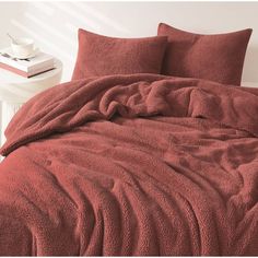 a bed with red sheets and pillows on it