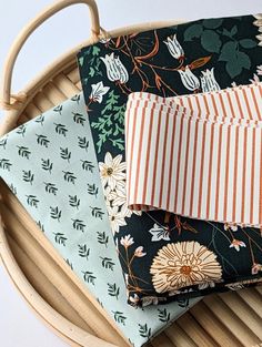 four pieces of fabric sitting on top of a wooden tray next to a basket with handles