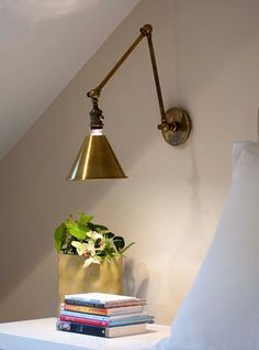 a lamp that is on the side of a wall next to books and a plant