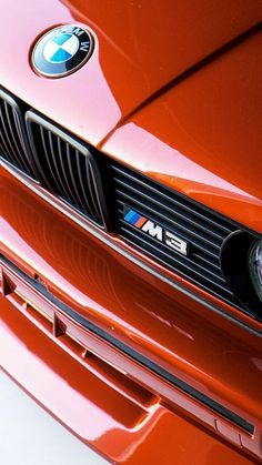 the front end of an orange bmw car with its emblem on it's grill