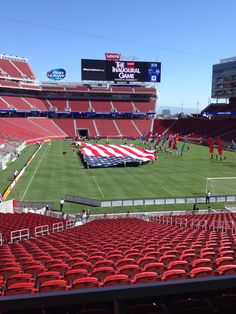 an empty stadium with red seats and a large american flag