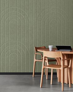 a wooden table and chairs in front of a green wall with geometric designs on it