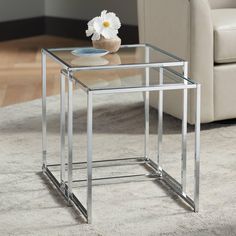 a glass table sitting on top of a rug next to a white flower in a vase