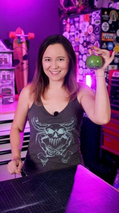 a woman holding an apple in her right hand and standing next to a counter top