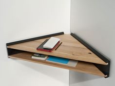 a wooden shelf with a book and notebook on it next to a wall mounted mirror