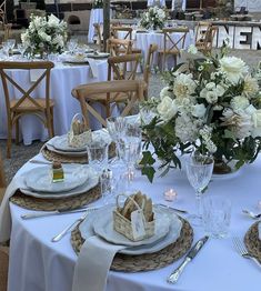 the table is set with white flowers and place settings