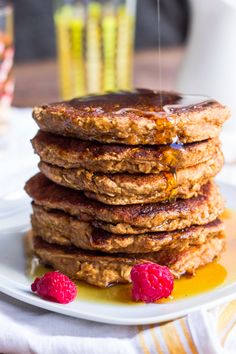 stack of pancakes with syrup and raspberries on plate