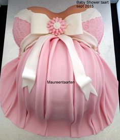 a baby shower tart cake with pink and white dress on it's back