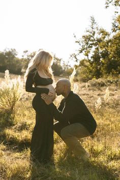 a man kneeling down next to a pregnant woman