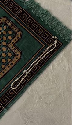 a close up of a green rug on a white surface with a chain hanging from it