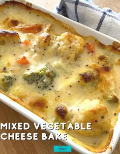 a casserole dish with cheese and vegetables in it on a wooden table next to a blue towel