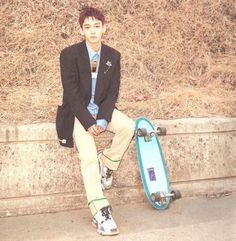 a young man sitting next to a skateboard