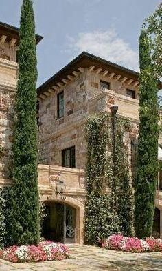 a large stone building with trees and flowers in the front yard