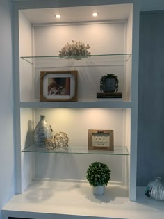 three shelves with vases, pictures and other items on them in a white room