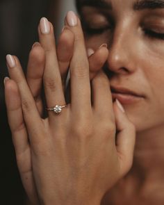 a close up of a person wearing a ring and holding their hand to her face