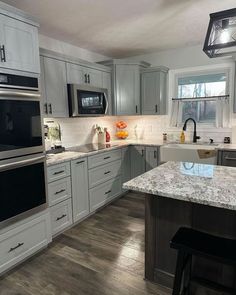 a large kitchen with white cabinets and granite counter tops, an island in the middle