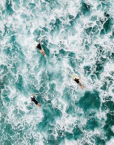 three surfers are in the ocean on their surfboards looking down at the waves