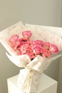 a bouquet of pink roses wrapped in paper