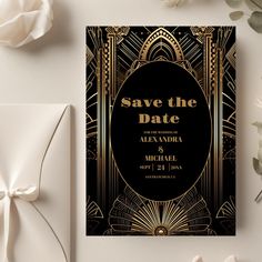 a black and gold art deco wedding save the date card on a table with white flowers