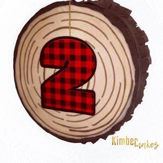 a red and black plaid number two hanging from a tree slice with the word 2 on it