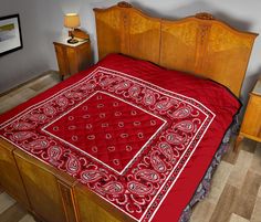 a bed with a red bedspread on top of it next to two nightstands