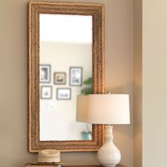 a table with a lamp and a mirror on it next to a wall mounted photo frame